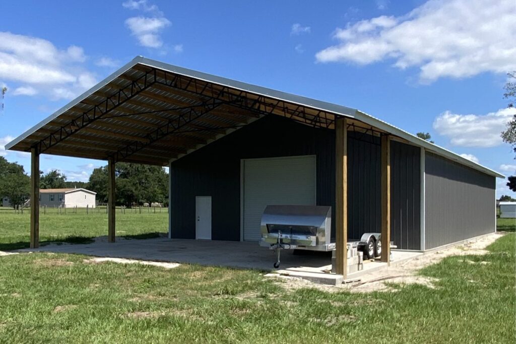 Open-sided metal pole barn used for equipment storage on a rural property built by Southern Pro Pole Barns & Buildings